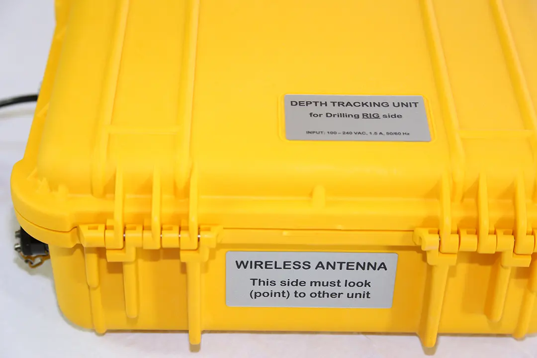 Closed yellow Remote Unit case. Labels read “Depth tracking unit, for drilling rig side, input 100–240 VAC, 1.5 A, 50/60 Hz” and “Wireless antenna: this side must point to other unit”.